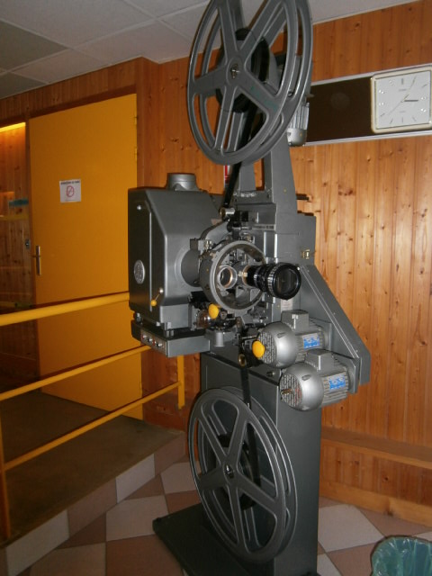 an old fashioned movie projector set in front of a wooden wall