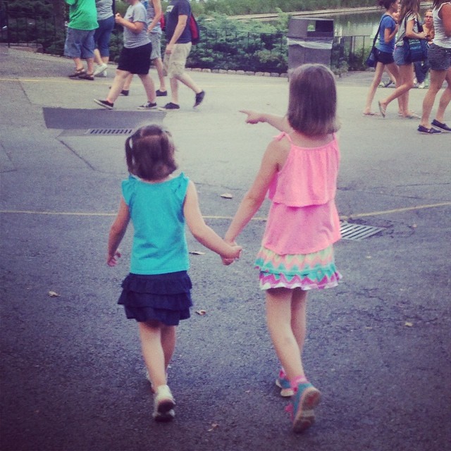 a couple of small girls walking down a street
