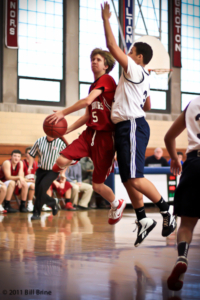 two people compete in a basketball game while onlookers watch