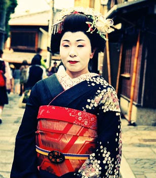 a geisha woman walking down an old alley way