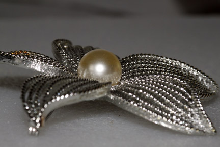 a gold pearl on top of a metal leaf brooch