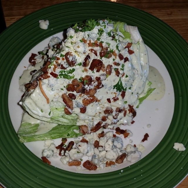 a green plate holding a piece of broccoli covered in ranch