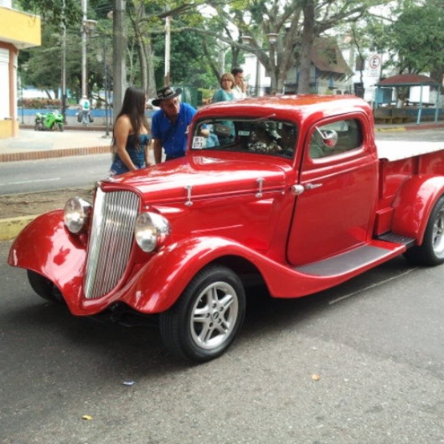 a vintage red car parked in the street