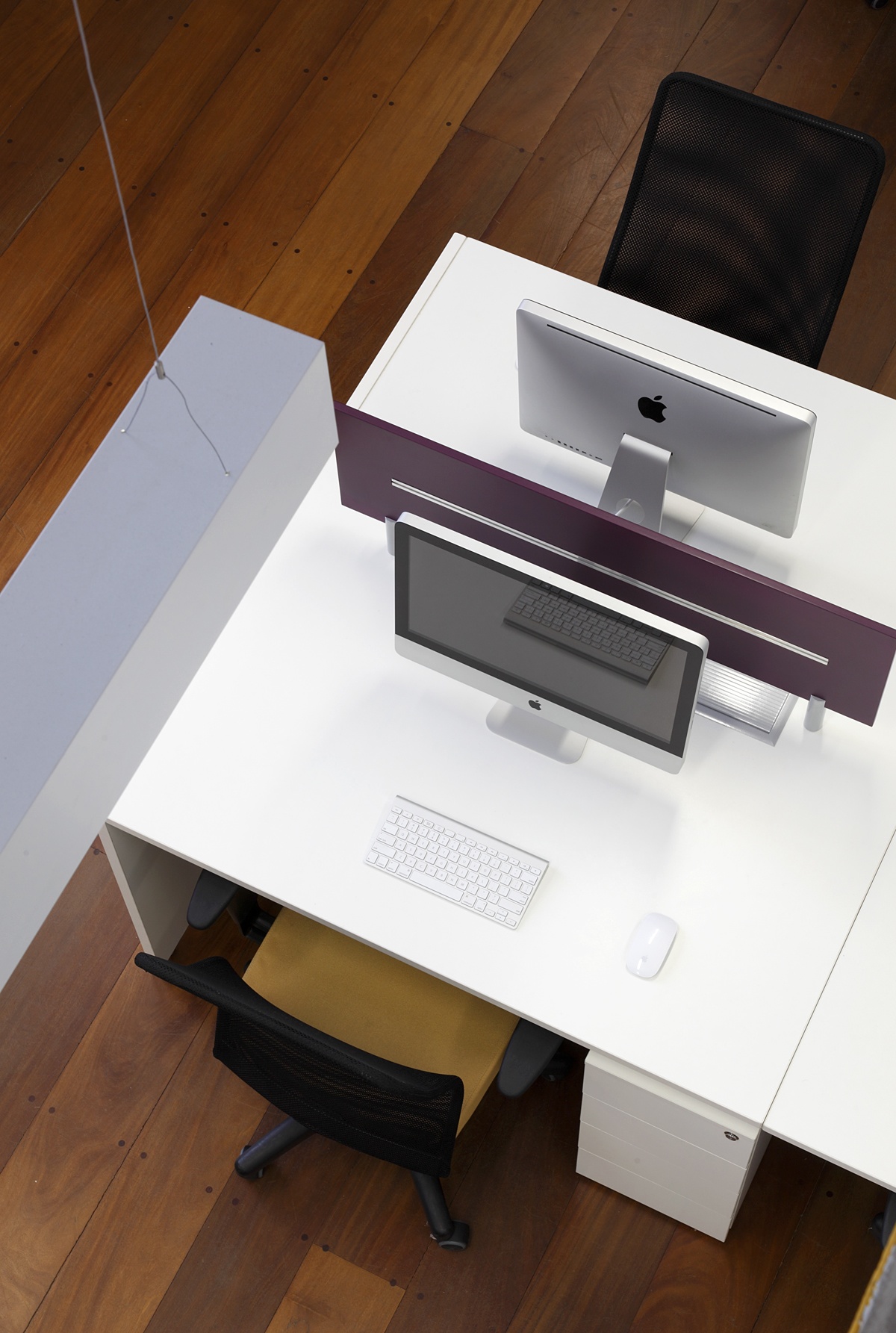 a desk with two computers on it and a chair in front