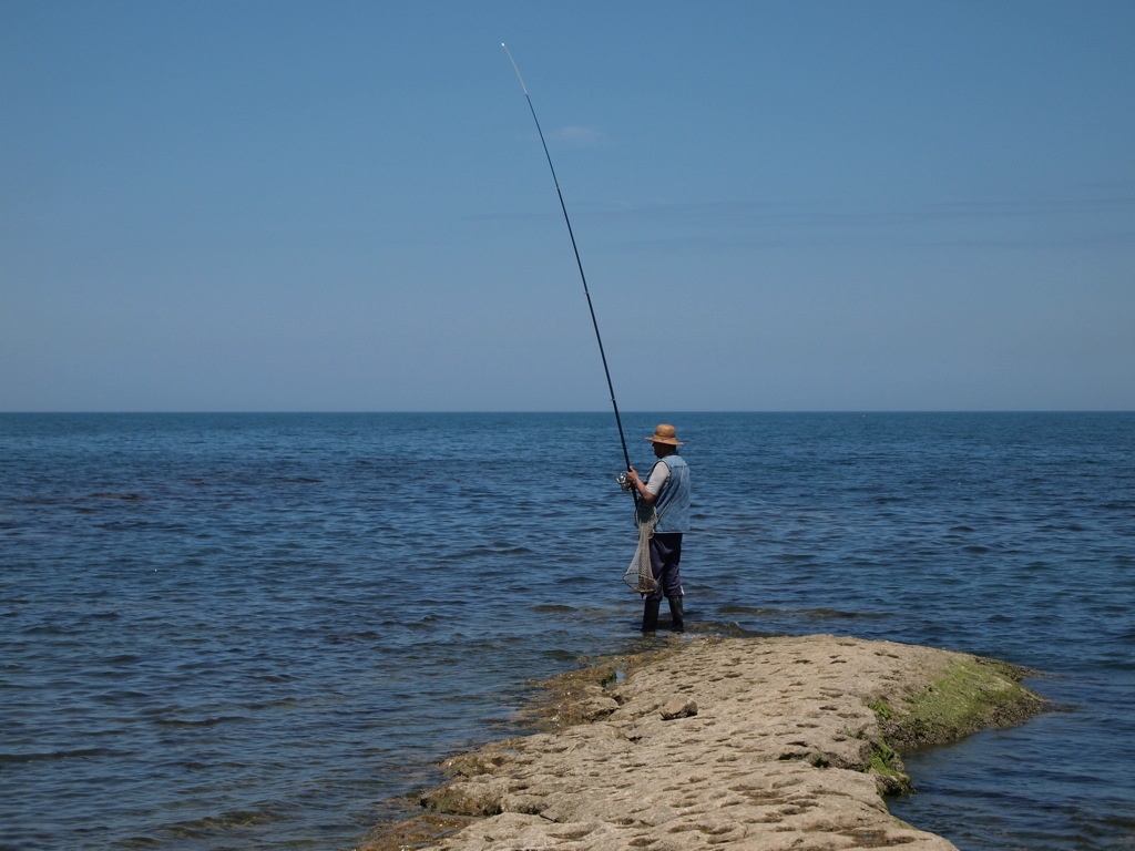 a man holding a fishing pole standing in the water
