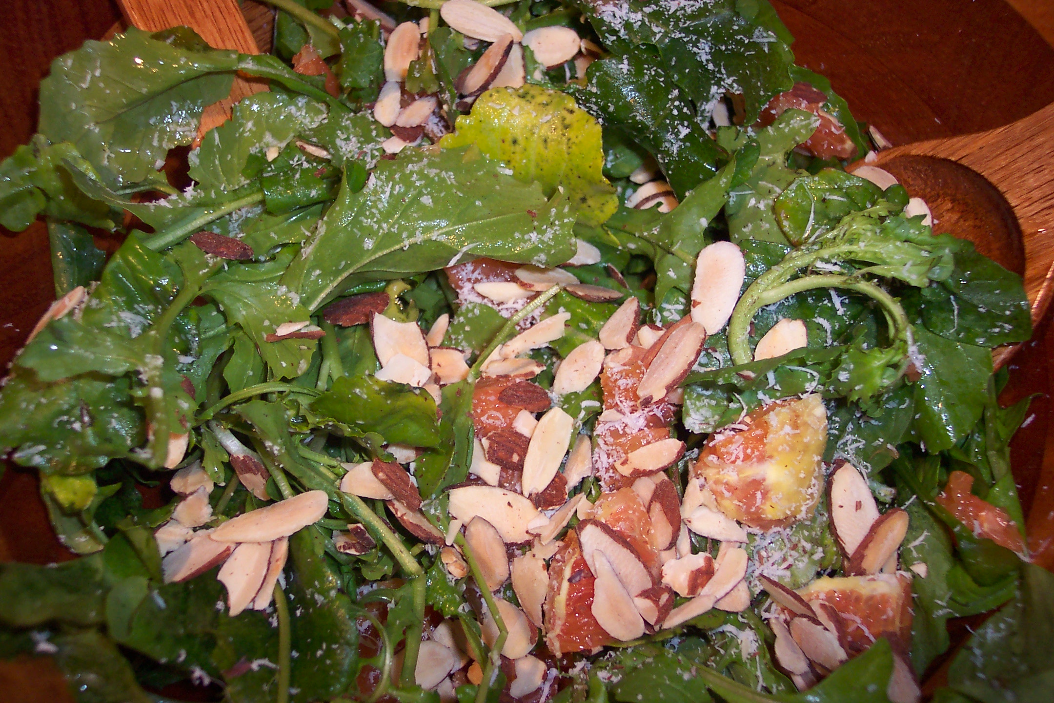 the salad has lettuce, spinach, almonds and cheese