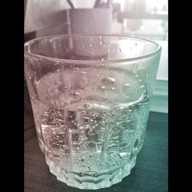a glass full of water sitting on top of a counter