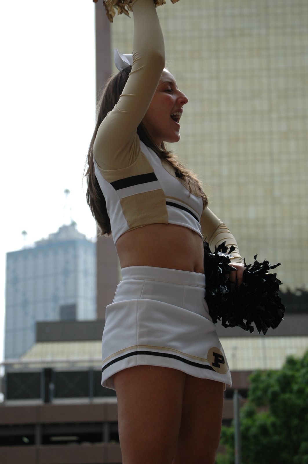 cheerleader in white uniform holds up her pom - poms