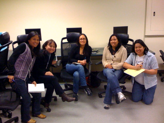 seven women pose for a po in front of a computer desk