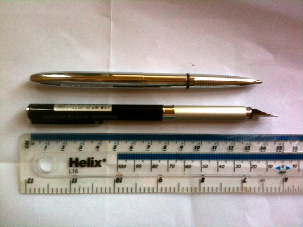 an old pen and ruler sitting next to each other