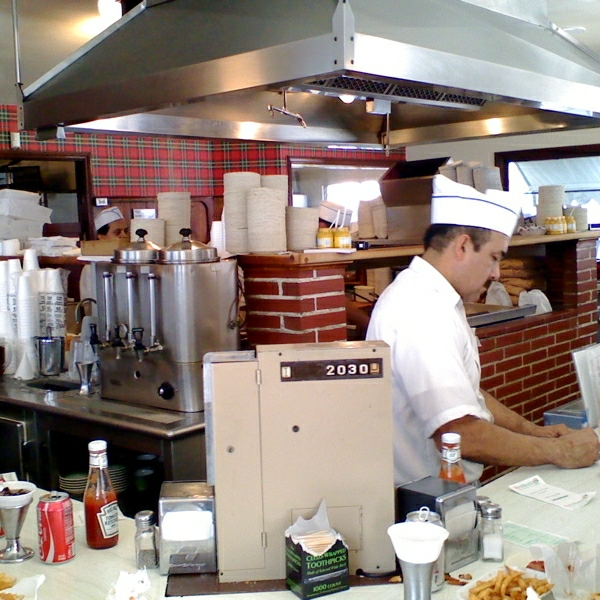 an industrial kitchen with a male worker in a white chef hat