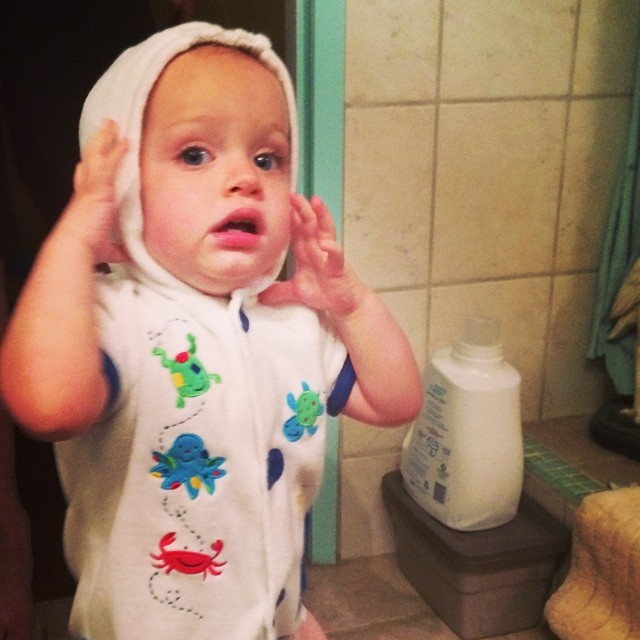 small child in a bathrobe brushing his teeth
