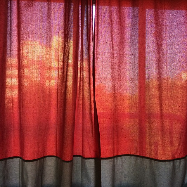 a red curtain with clouds behind it next to a black window