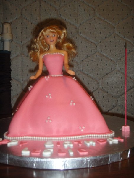 a barbie doll cake with a little stick on it