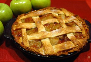 an apple pie in a pan next to apples