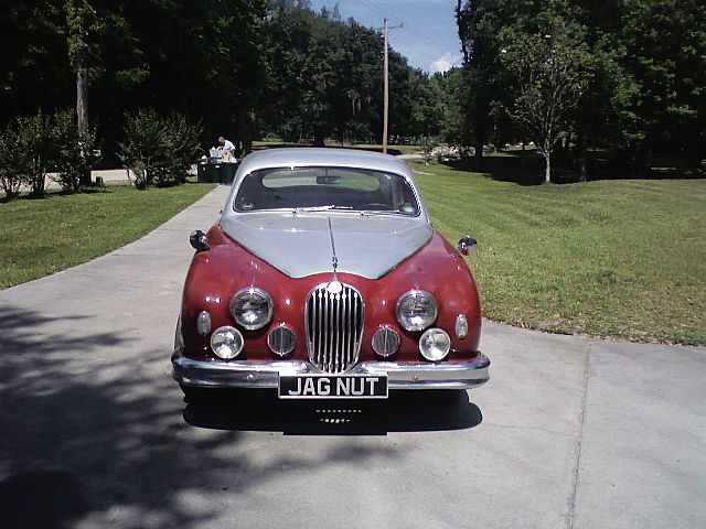 an old red car is parked next to a sidewalk