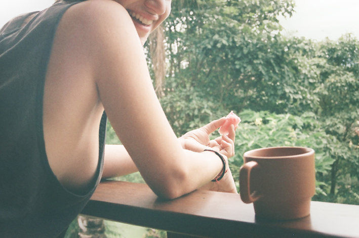 a smiling young woman holding onto a coffee cup