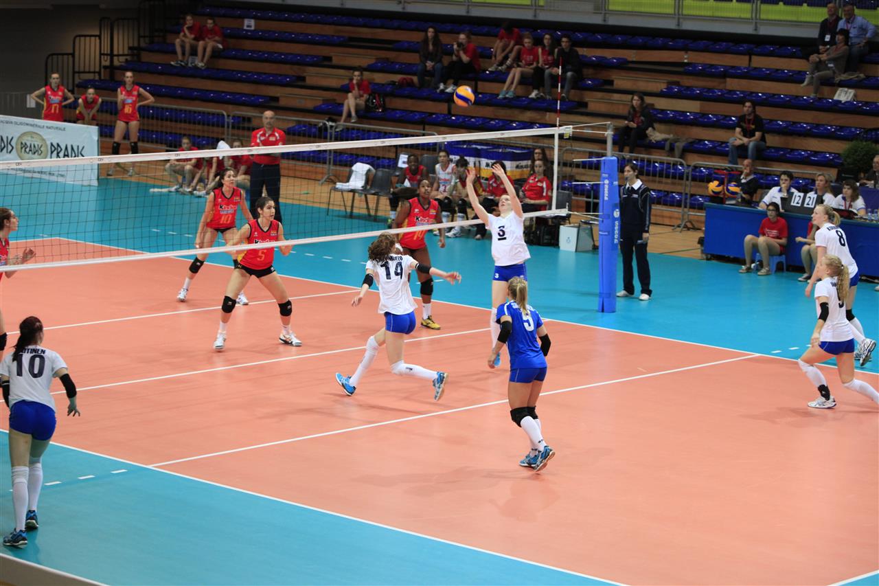 volleyball players playing a game of volleyball on an indoor court