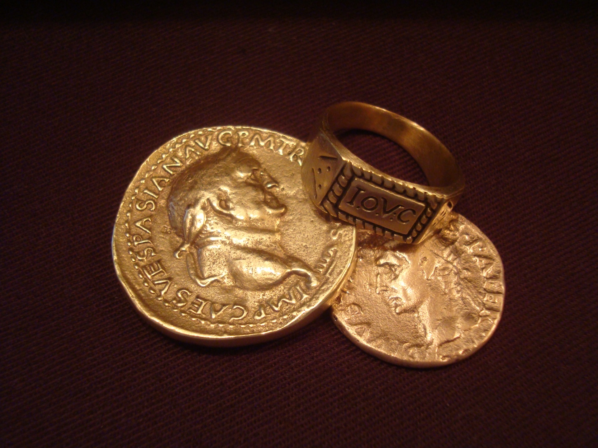 an ancient greek coin ring is placed beside two greek coins