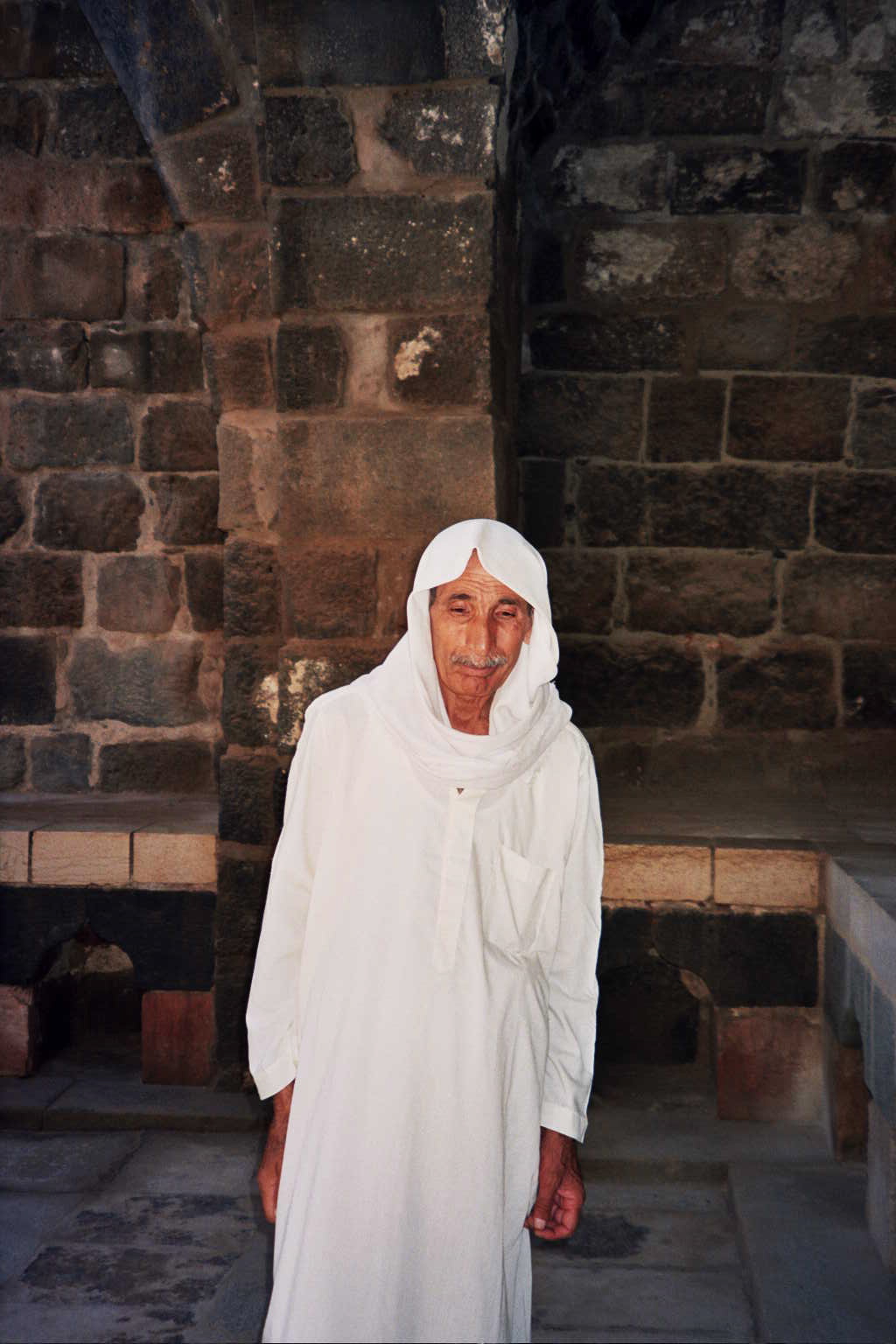 a old man dressed in white standing by some steps