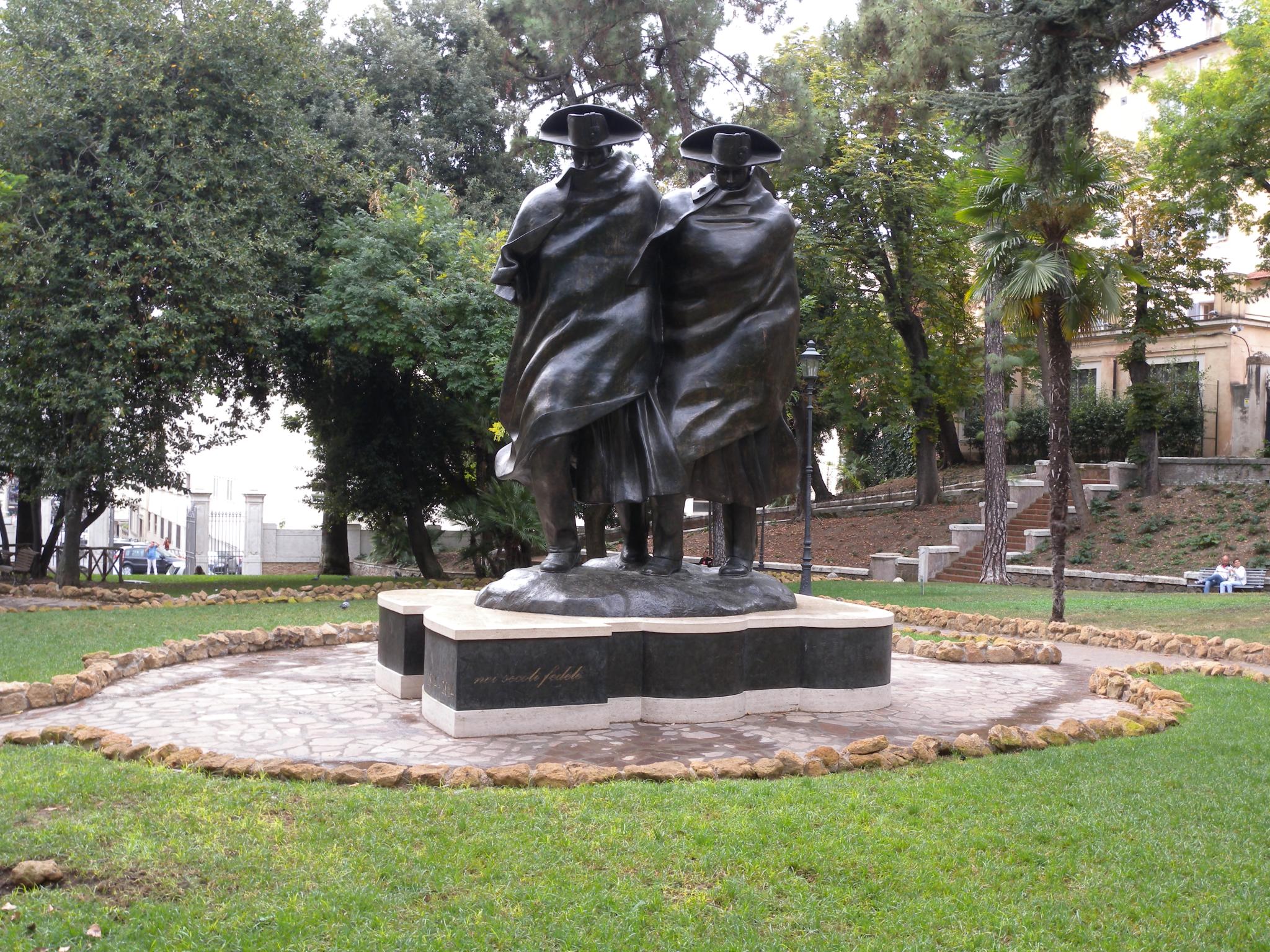 a bronze statue of a man with a coat and hat