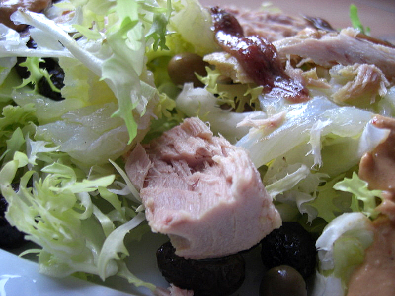 a closeup of a plate of food with lettuce, olives and meat