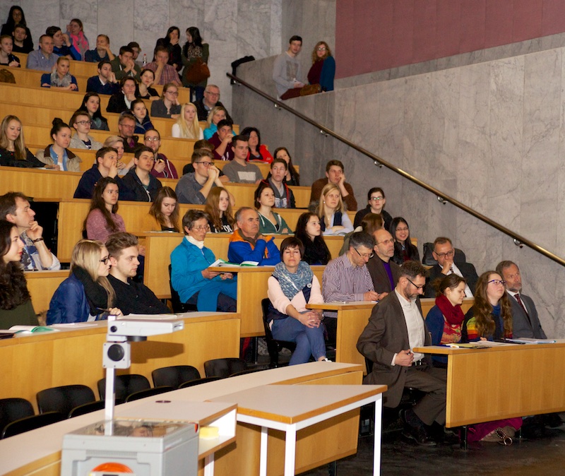 people sitting in lecture style seats on the stage