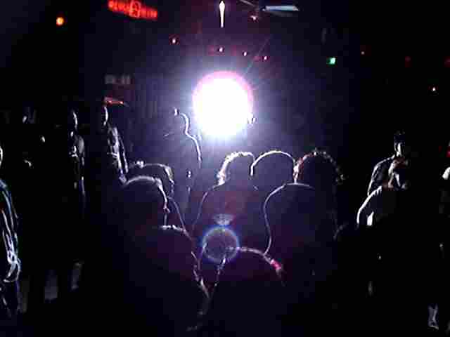 a group of people standing next to a dark street at night