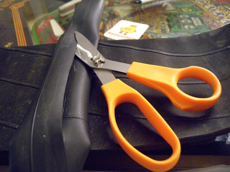 some scissors with orange handles on a piece of black leather