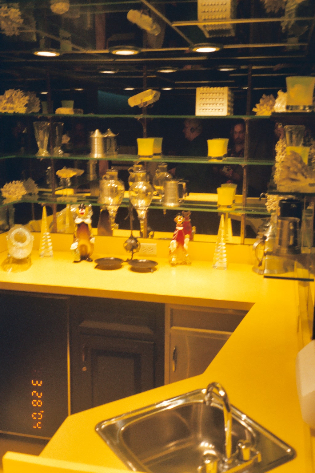 yellow painted kitchen area with shelves full of glass objects and decorations