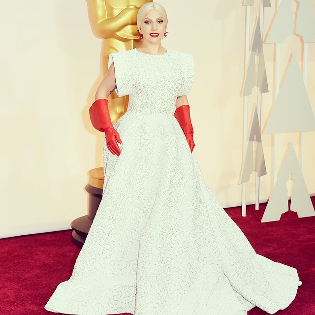 lady in white dress and red gloves at oscars