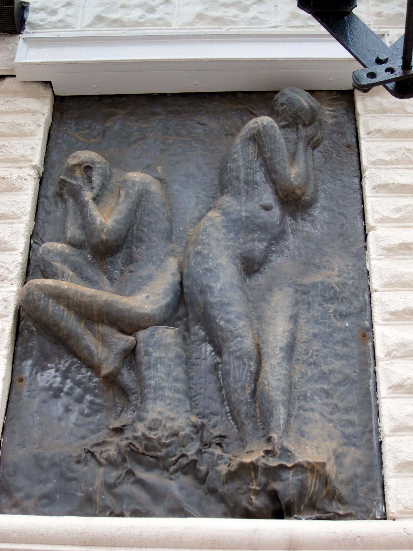 a statue of two girls sitting on their knees in front of a window