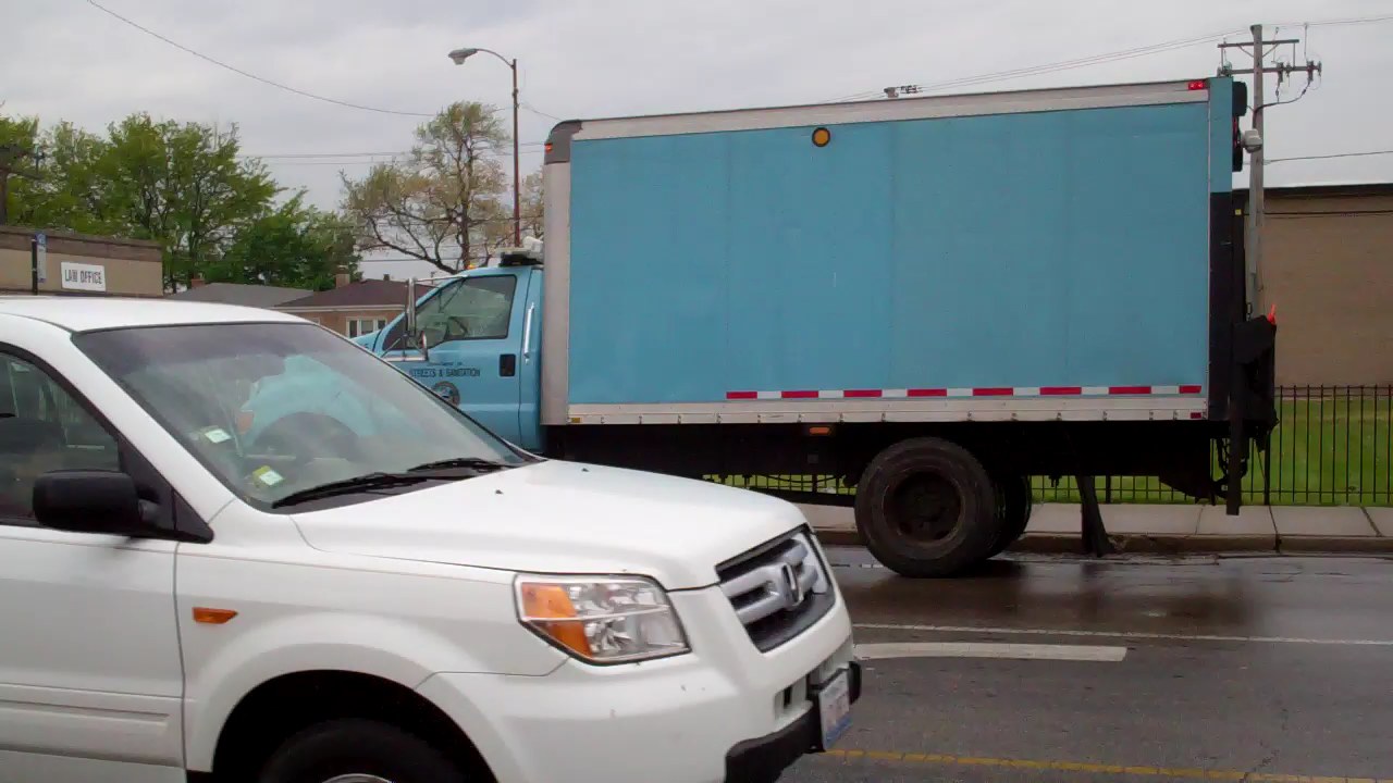a white and blue truck driving down the street