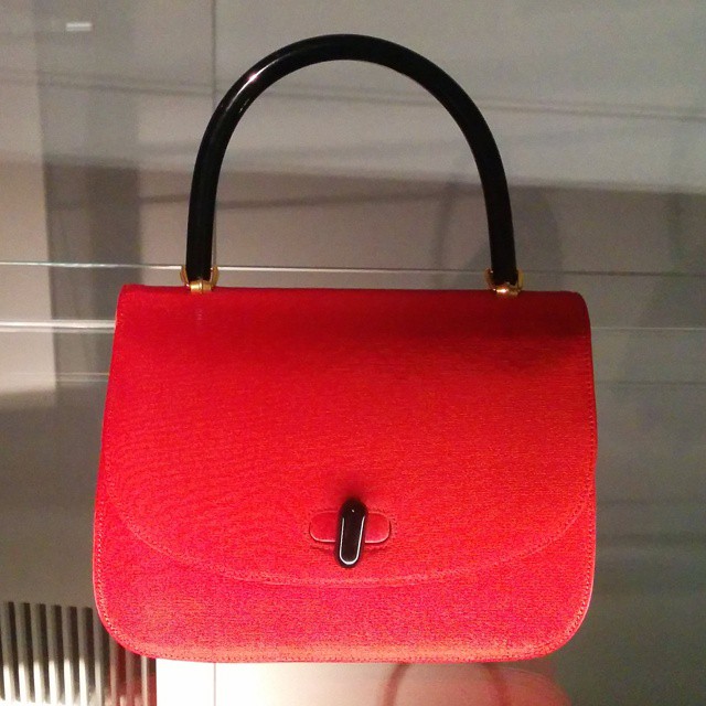 a woman holding a red purse that has two handles
