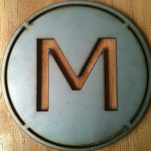 metal emblem on wood board with letter m