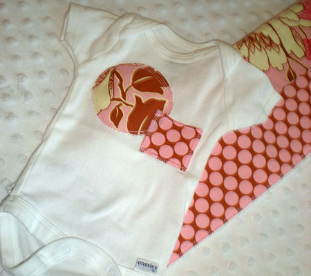 two pink and brown heart shaped onesie onesies are lying on a bed