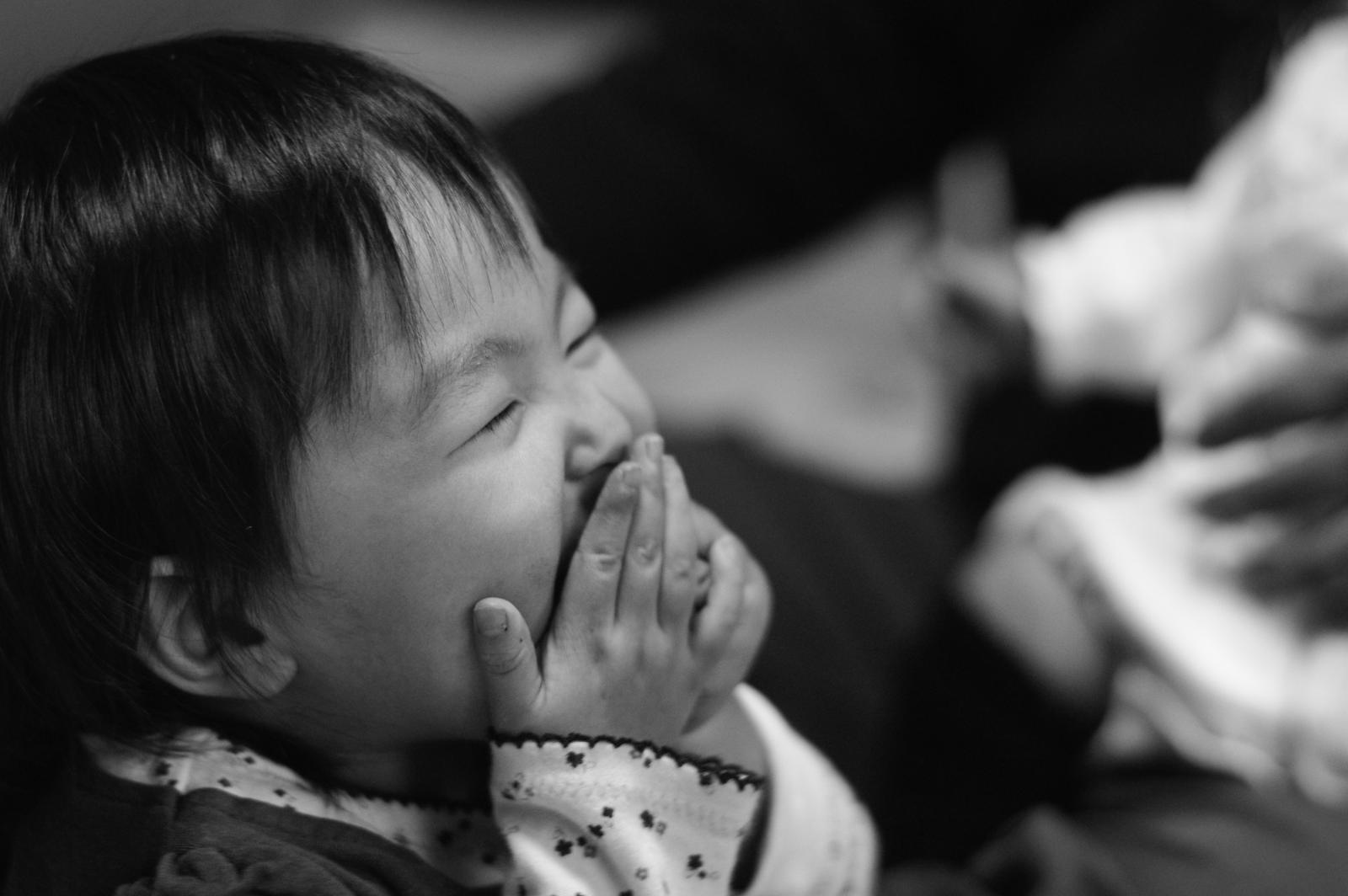 black and white pograph of child holding hands to mouth