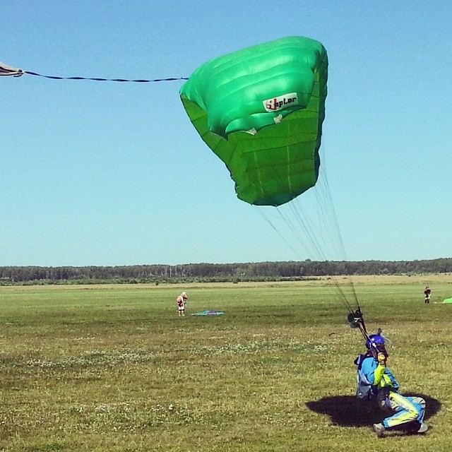 three people fly kites in an open field