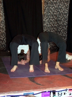two people stand on one side with their arms in the air on purple mat