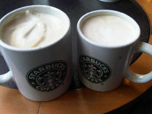 two white coffee mugs with cream on a table
