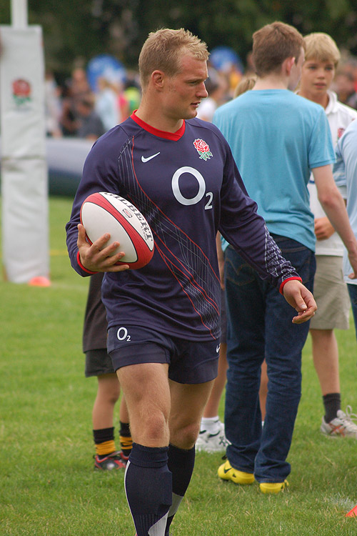 an athlete carries a rugby ball in a grassy area