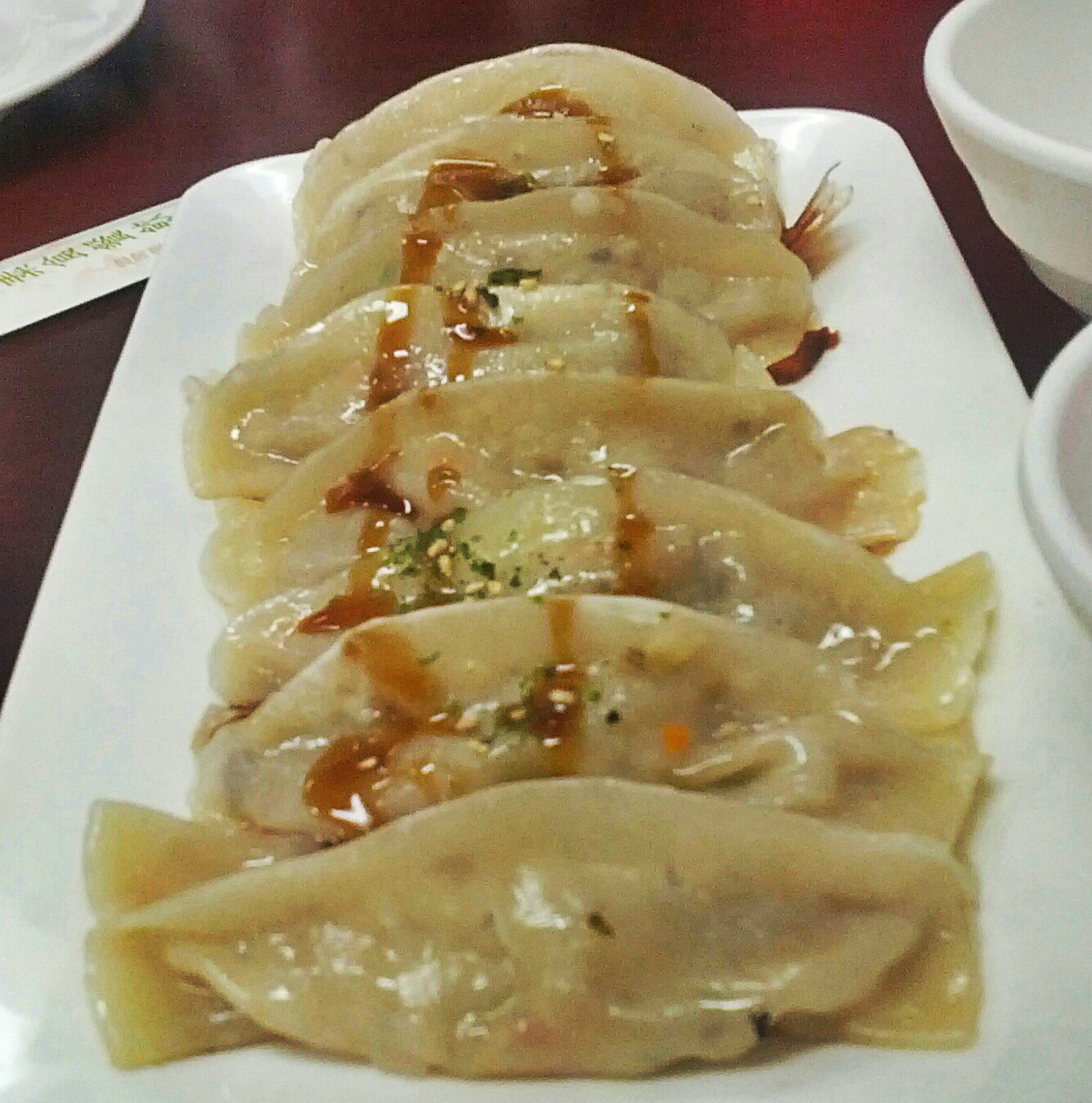 several asian dumplings covered in sauce on a plate