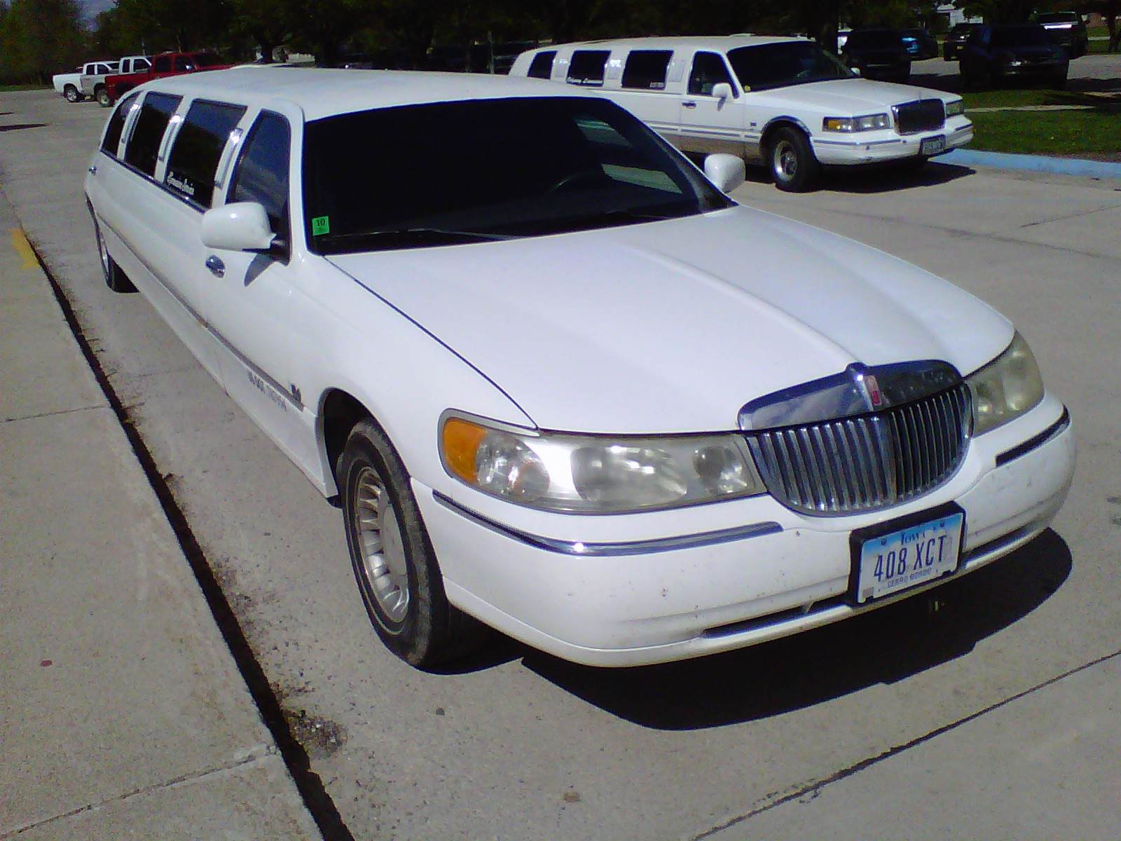 a white limousine parked on the curb near other cars