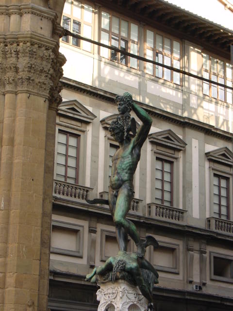 a statue is near a building by the water