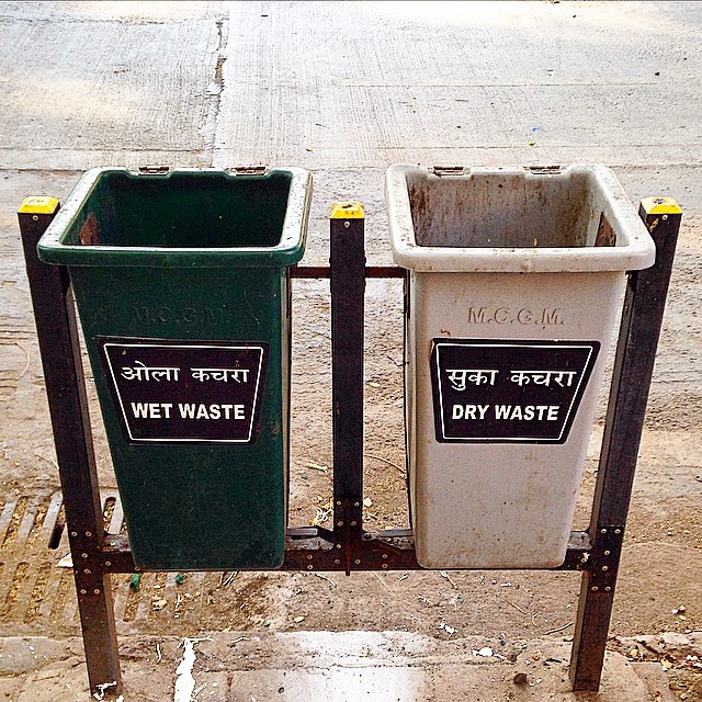 two garbage cans sitting next to each other on a sidewalk