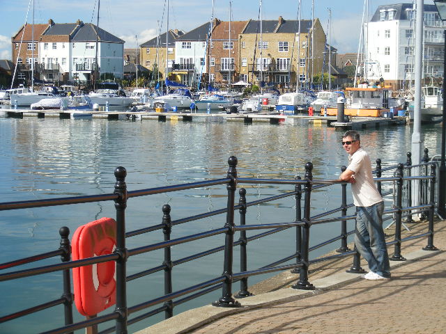 the man is standing next to the railing near the water