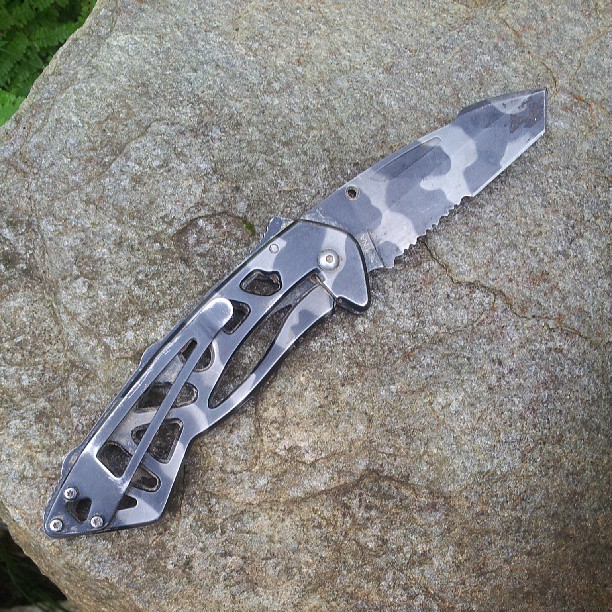 a knife with camouflaged paint on the blade on a rock
