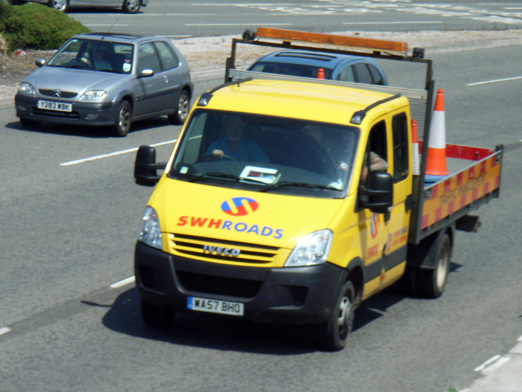 a yellow truck on the road with two cars