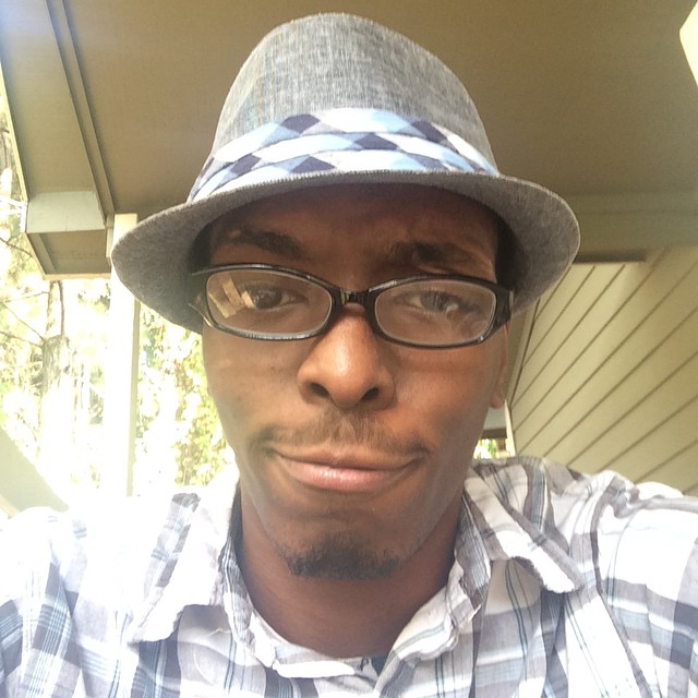 a man wearing a hat, glasses and checkered shirt