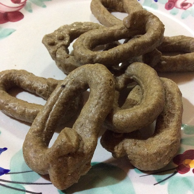 several dog snacks made of raw pretzels on a flowered plate